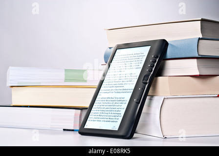 E-Book appoggiata contro una pila di libri stampati. Foto Stock
