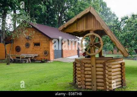 Ben rurale tombino decorazione e casa fatta di tronchi di legno nel paese homestead. Foto Stock