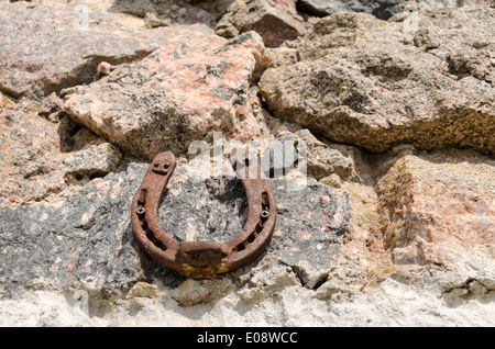 Vecchio ferro vintage fortune a ferro di cavallo simbolo sul muro di pietra sullo sfondo Foto Stock