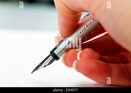 Una mano con una fontana-penna con il Untrerschrift sotto un contratto o un testamento., Eine mano mit einer Fuellfeder bei der Untrers Foto Stock