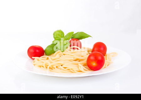 Spaghetti con pomodorini e basilico su sfondo bianco Foto Stock