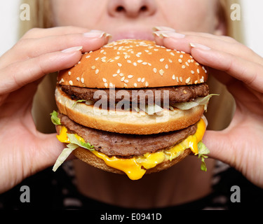 Donna di mangiare un hamburger, vicino. Foto Stock