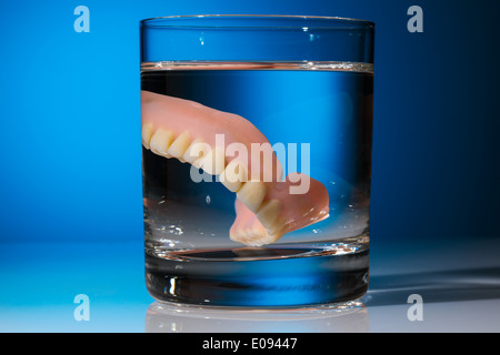 Una serie di protesi viene pulita in un bicchiere con acqua. Diritto igiene., Ein Zahnersatz wird in einem Glas mit Wasser gereinigt. Ricca Foto Stock