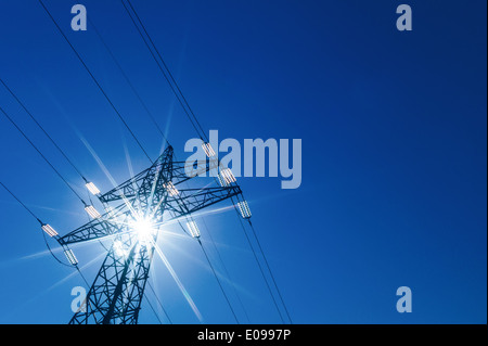 Da montanti di una gestione Hochspannungs fue flusso elettrico sembra il sun. Energia solare, durch einen Masten einer Hochspannungs L Foto Stock