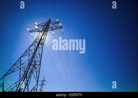 Da montanti di una gestione Hochspannungs fue flusso elettrico sembra il sun. Energia solare, durch einen Masten einer Hochspannungs L Foto Stock