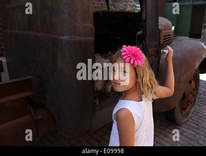 Ritratto di una giovane ragazza bionda in un abito bianco con un fiore rosa fermaglio per capelli in possesso di una portiera di un vintage pickup truck, Toronto Foto Stock