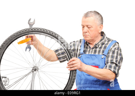 Matura meccanico di bicicletta guardando una ruota Foto Stock