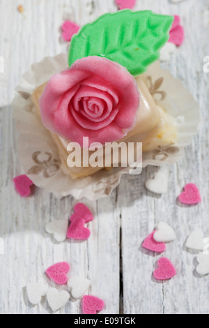 Petit Four decorata con rose di marzapane in legno grigio Foto Stock