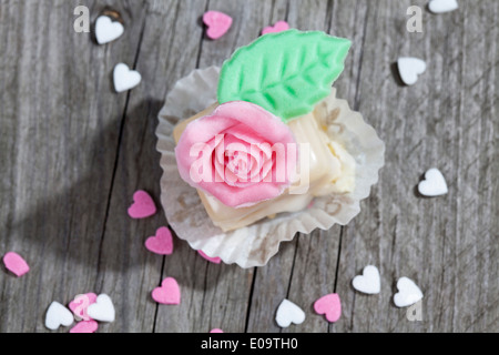 Petit Four decorata con rose di marzapane in legno grigio Foto Stock