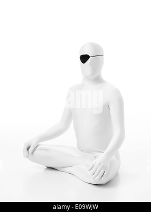 L'uomo senza volto vestito di bianco seduto sul pavimento con un occhio pirata Foto Stock