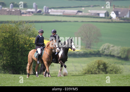 Due cavalli e cavalieri godendo di una passeggiata attraverso la campagna Foto Stock