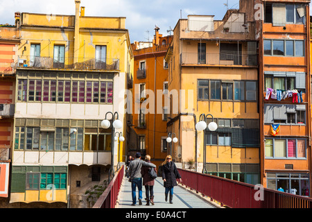 Le persone che attraversano ponti Circondato da colorati edifici lungo il fiume Onyar, Girona, Catalogna, Spagna Foto Stock