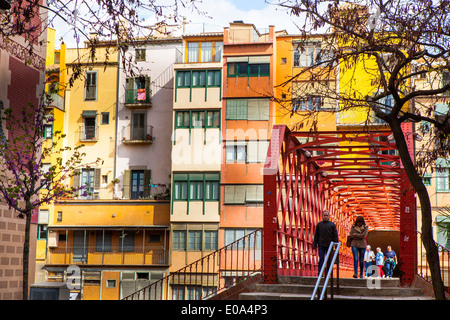 Le persone che attraversano le Palanques ponte Vermelles Circondato da colorati edifici lungo il fiume Onyar, Girona, Catalogna, Spagna Foto Stock