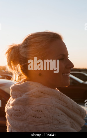 Sorridente metà donna adulta nel parcheggio al tramonto Foto Stock