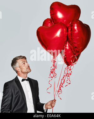 Ritratto di uomo in smoking con heart-shaped balloons Foto Stock