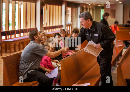 Sacerdote cattolico saluta i giovani ispanici parrocchiani prima messa in una Laguna Niguel, CA, chiesa cattolica. Foto Stock