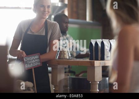 Femmina giovane cameriera di consulenza sulla scelta di caffè nella caffetteria Foto Stock