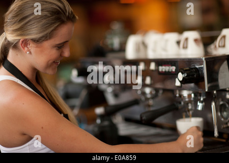 Femmina giovane cameriera di preparazione di caffè nella caffetteria Foto Stock