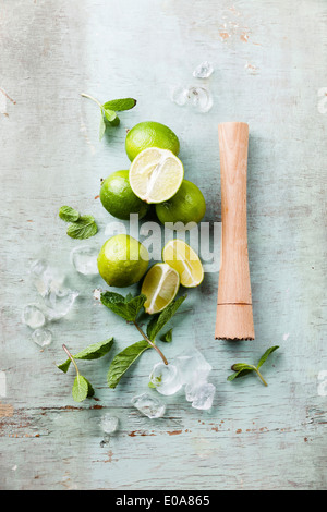 Ingredienti per rendere mojitos di cubetti di ghiaccio, foglie di menta e calce su sfondo blu Foto Stock