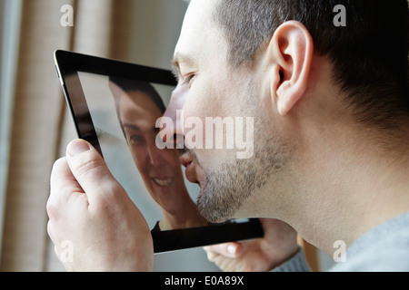 Metà uomo adulto kissing schermo della tavoletta digitale Foto Stock