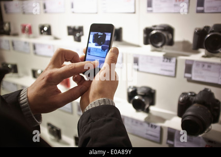 Metà uomo adulto fotografare la fotocamera in negozio il display utilizza lo smartphone Foto Stock