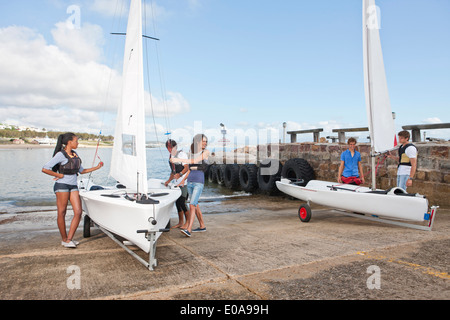 Giovani amici adulti la preparazione di barche a vela sul lungomare Foto Stock