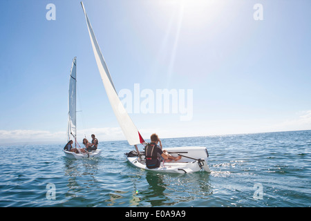 Giovani amici adulti racing a vicenda nelle barche a vela Foto Stock