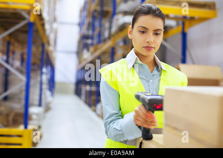 Giovane donna con il lettore di codici a barre nel magazzino di distribuzione Foto Stock