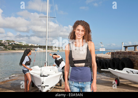 Ritratto di giovane donna con amici la preparazione di barca a vela Foto Stock