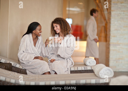 Due giovani donne in chat sui lettini a spa Foto Stock