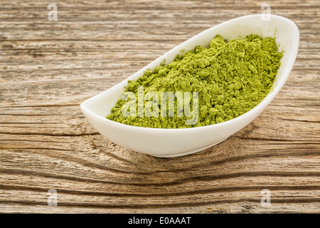 Moringa leaf in polvere in una piccola ciotola di ceramica contro la venatura del legno Foto Stock