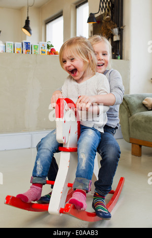 Due giovani sorelle giocando sul cavallo a dondolo Foto Stock