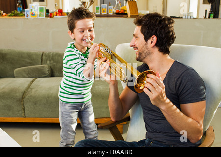 Padre incoraggiando giovane figlio suonare la tromba Foto Stock