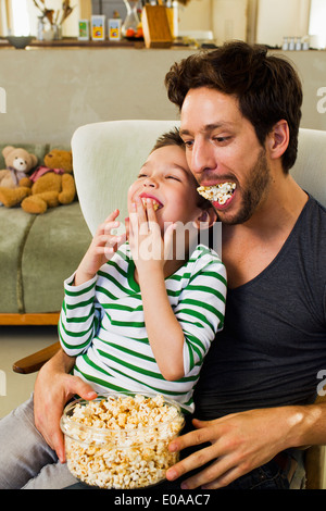 Padre e figlio giovane con bocconi di popcorn Foto Stock