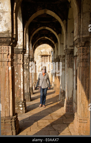 Donna che cammina in colonnato a Jami Masjid (Grande Moschea), Champaner-Pavagadh Parco Archeologico, Gujarat, India Foto Stock