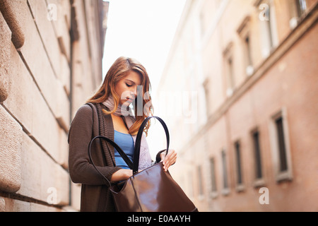 Giovane donna ricerca con ansia la sua borsa a tracolla Foto Stock