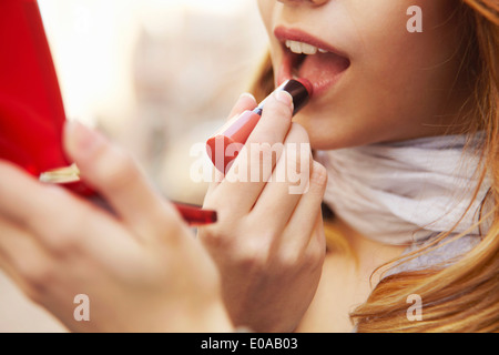 Close up della giovane donna mettendo sul rossetto Foto Stock