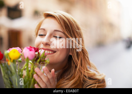 Sorridente giovane donna odorare un mazzo di fiori Foto Stock