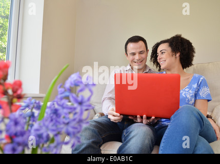 Giovane rilassante sul divano con il computer portatile Foto Stock