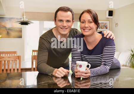 Ritratto di metà adulto giovane appoggiata sul banco di cucina Foto Stock