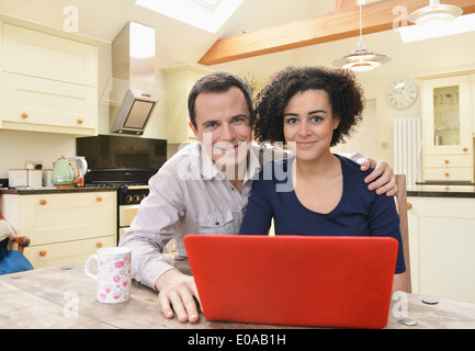 Ritratto di giovane con computer portatile sul tavolo da cucina Foto Stock