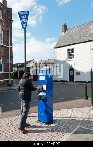 Donna acquisto di un parcheggio auto biglietto da una macchina sul martedì Market Place, King's Lynn, Norfolk. Foto Stock