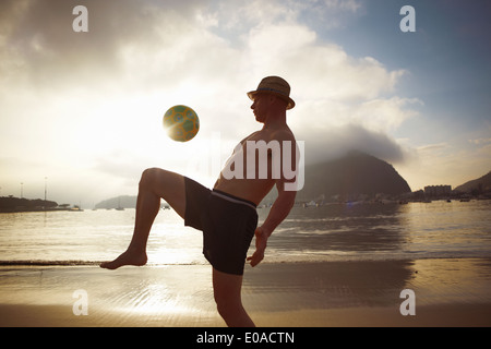 Metà uomo adulto giocando keepy uppy sulla spiaggia di Botafogo, Rio de Janeiro, Brasile Foto Stock