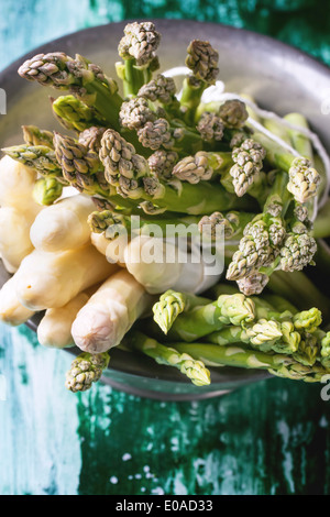 Mazzetto di verde giovane e asparagi bianchi in metallo vintage ciotola verde su un tavolo di legno. Vista superiore Foto Stock