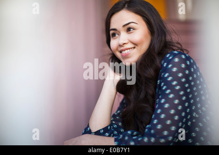 Giovane donna sorridente e guardando lontano Foto Stock