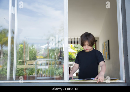 Ragazzo la lettura del suo libro a finestra aperta Foto Stock