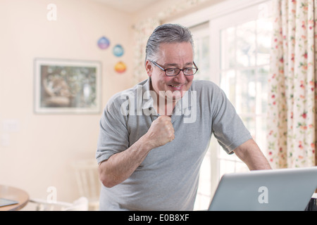 Uomo maturo celebrare mentre guardando il computer portatile Foto Stock