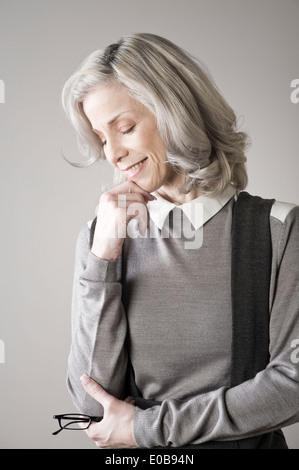 Donna matura con mano sul mento, sorridente Foto Stock