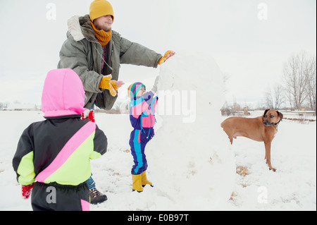Padre e figli La costruzione di pupazzo di neve Foto Stock