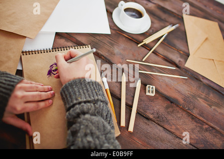 Immagine della tazza di caffè e oggetti per il disegno a mano e mani dell'artista con la penna sul blocco note Foto Stock